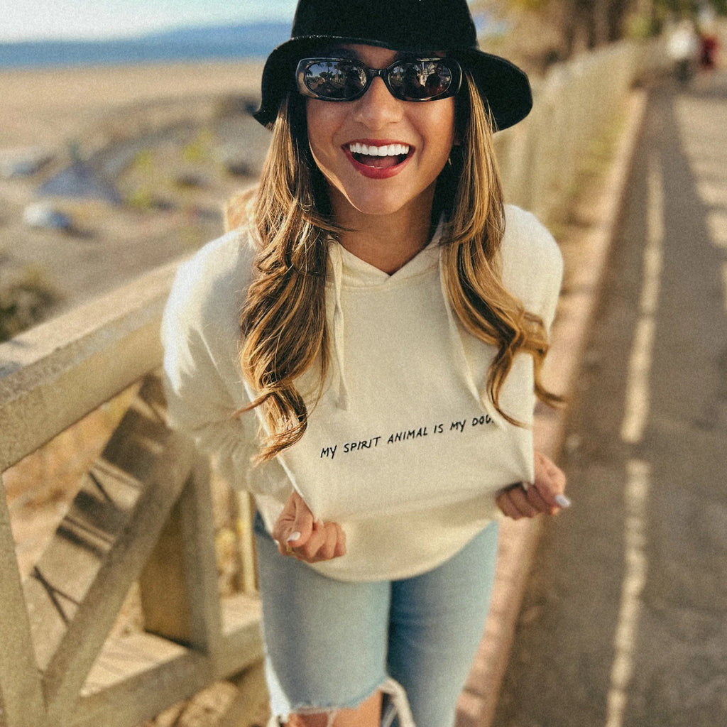 Image Details: Alt Text: A radiant model proudly showcases her 'My Spirit Animal Is My Dog' hoodie, smiling at a park perched on a cliff with a breathtaking ocean view in Santa Monica.