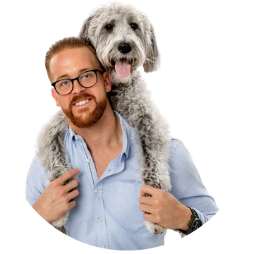 JB Hill, the founder of Westside Dog Gang, wearing a warm smile in his headshot, with his beloved doodle companion, Sofi, happily perched on his shoulder, tongue out and smiling.